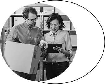 Man and woman in warehouse holding abox and checking a tablet