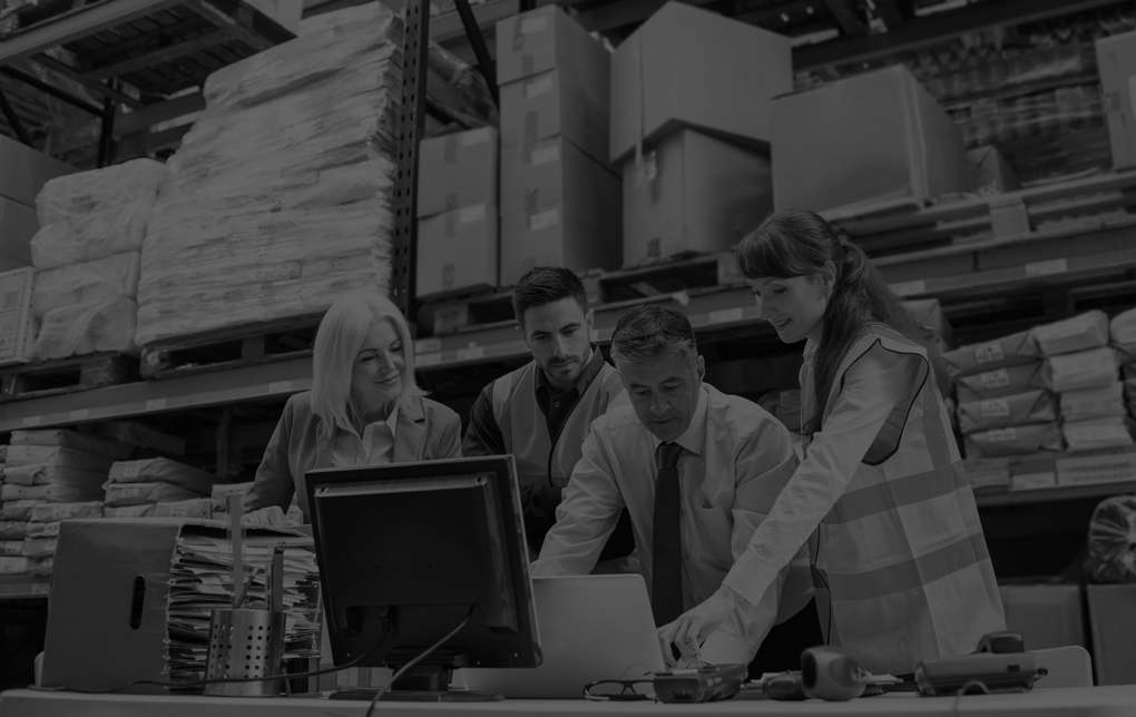 Warehouse managers and worker working on laptop in a large warehouse