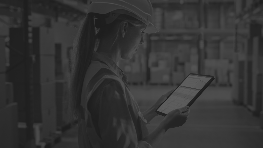 Professional Female Worker Wearing Hard Hat Uses Digital Tablet Computer with Inventory Checking Software in the Retail Warehouse full of Shelves with Goods.