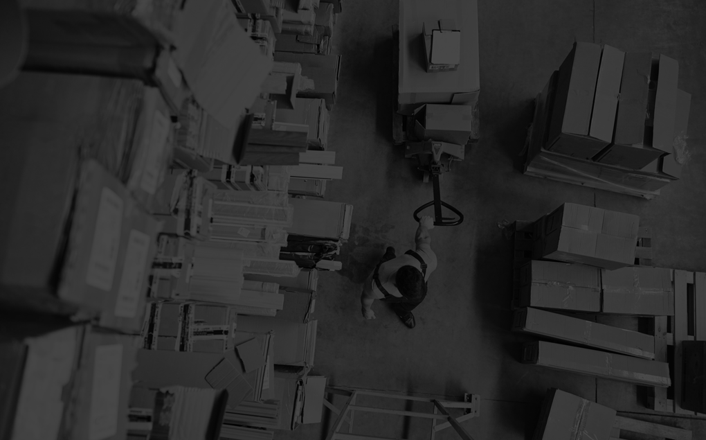 Top-Down View: Worker Moves Cardboard Boxes using Hand Pallet Truck, Walking between Rows of Shelves with Goods in Retail Warehouse.