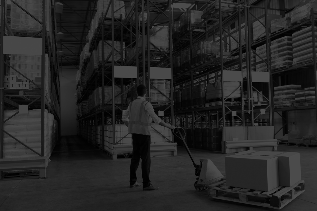 Rear-view-of-male-staff-using-pallet-jack-in-warehouse.-This-is-a-freight-transportation-and-distribution-warehouse.