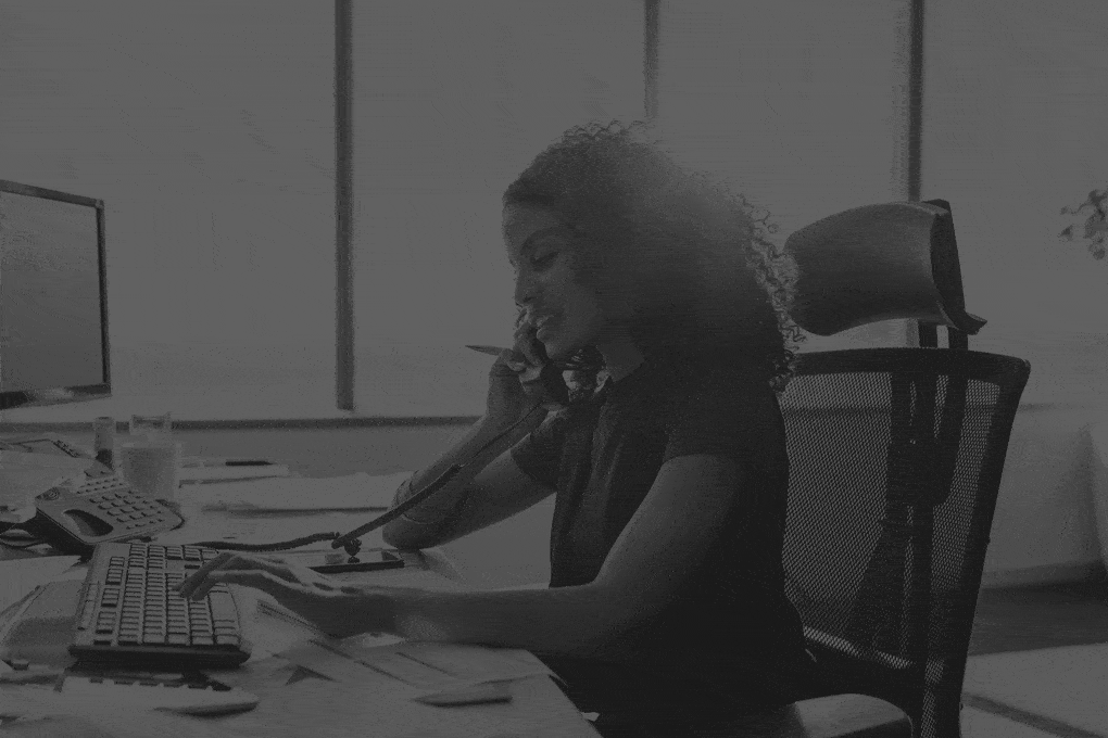 Woman-entrepreneur-busy-with-her-work-in-office.-Young-woman-talking-over-telephone-while-working-on-computer-at-her-desk.