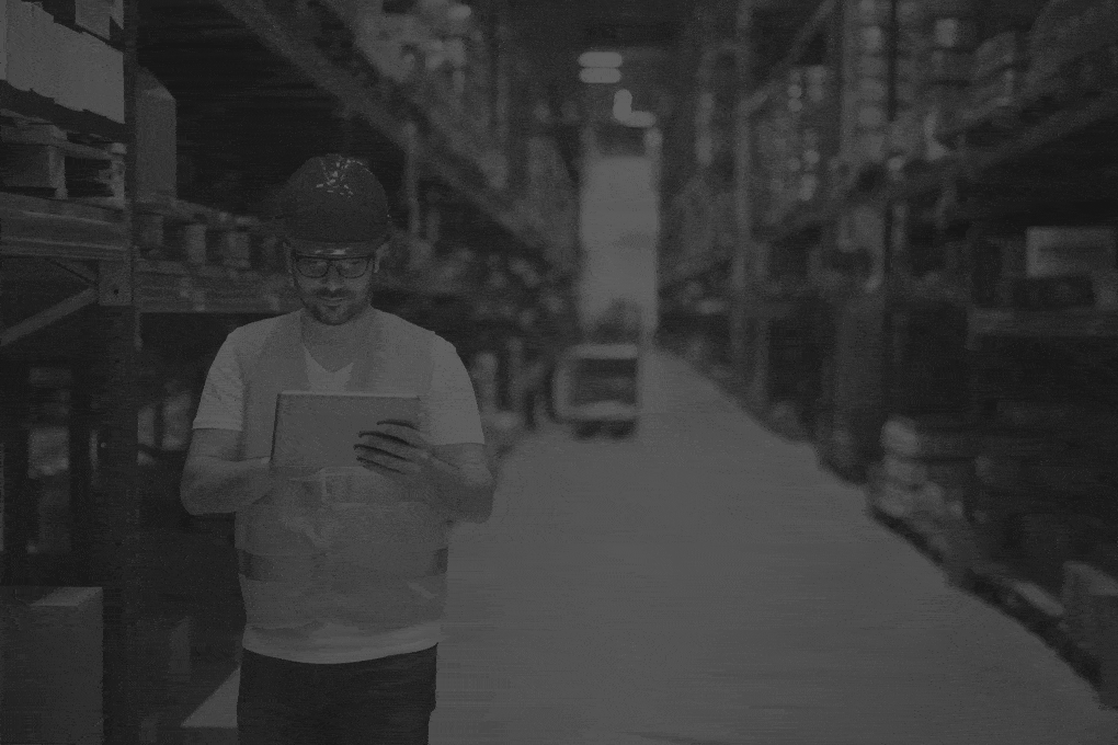 man-walking-through large-warehouse-storage-storehouse-center-and-using-tablet