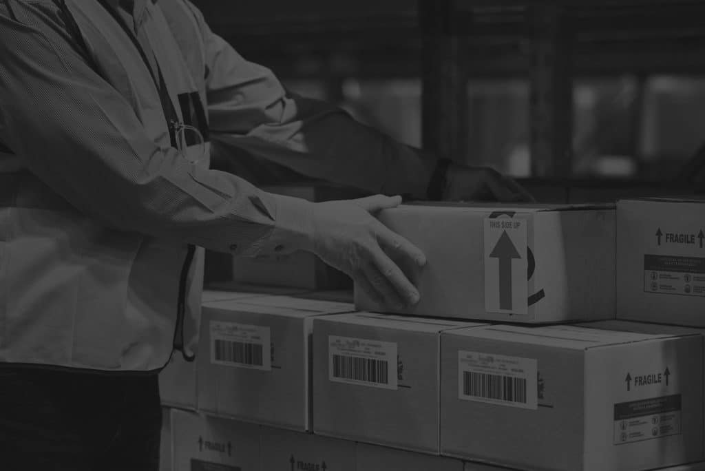 man in warehouse conducting inventory management with box in black and white