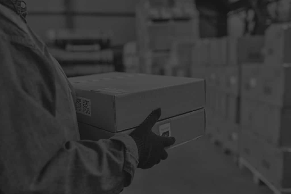 Closeup of worker carrying boxes in a warehouse. Image in black and white.