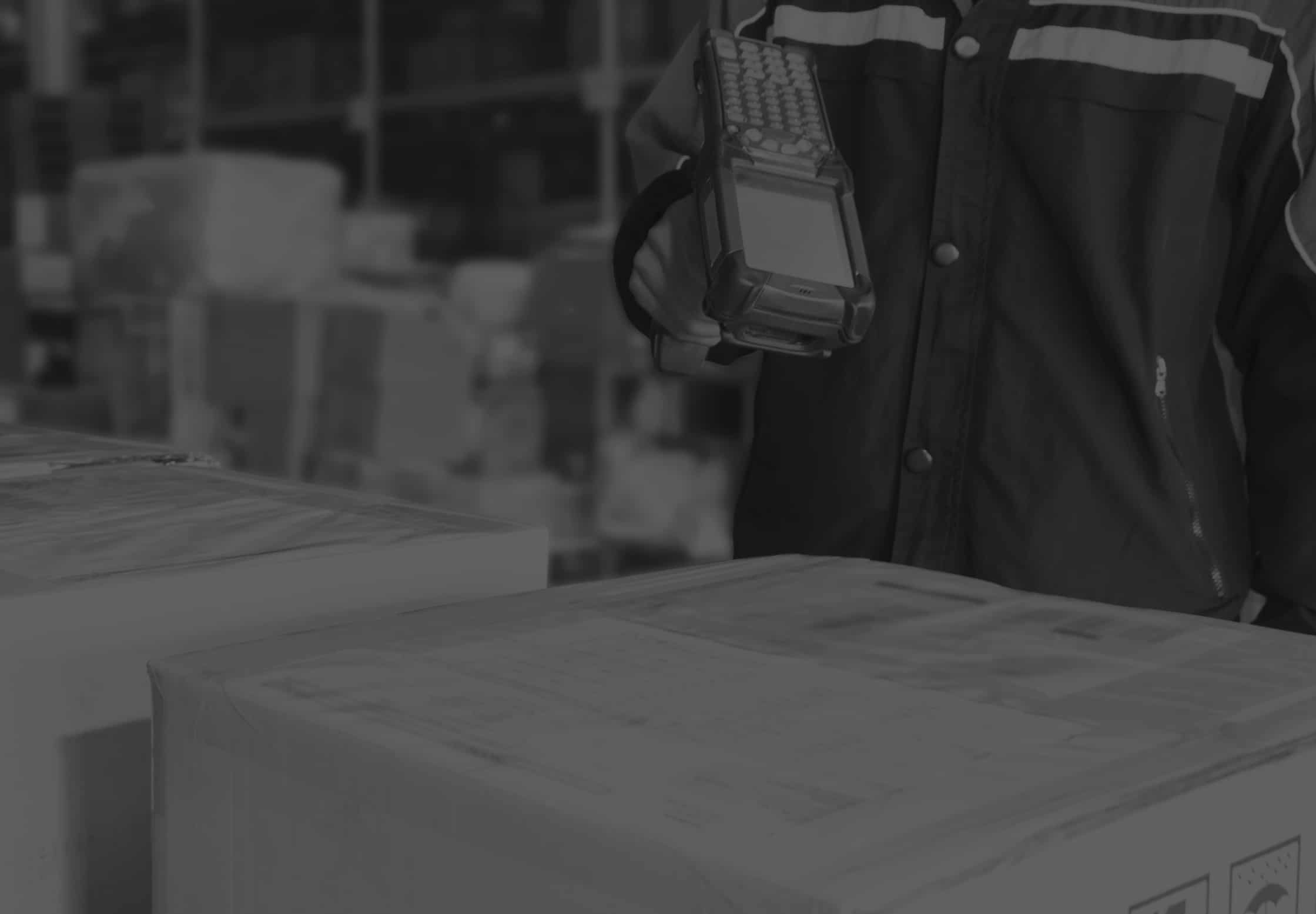 Cloesup of warehouse worker using barcode scanner to scan a box in a warehouse. Black and white image.