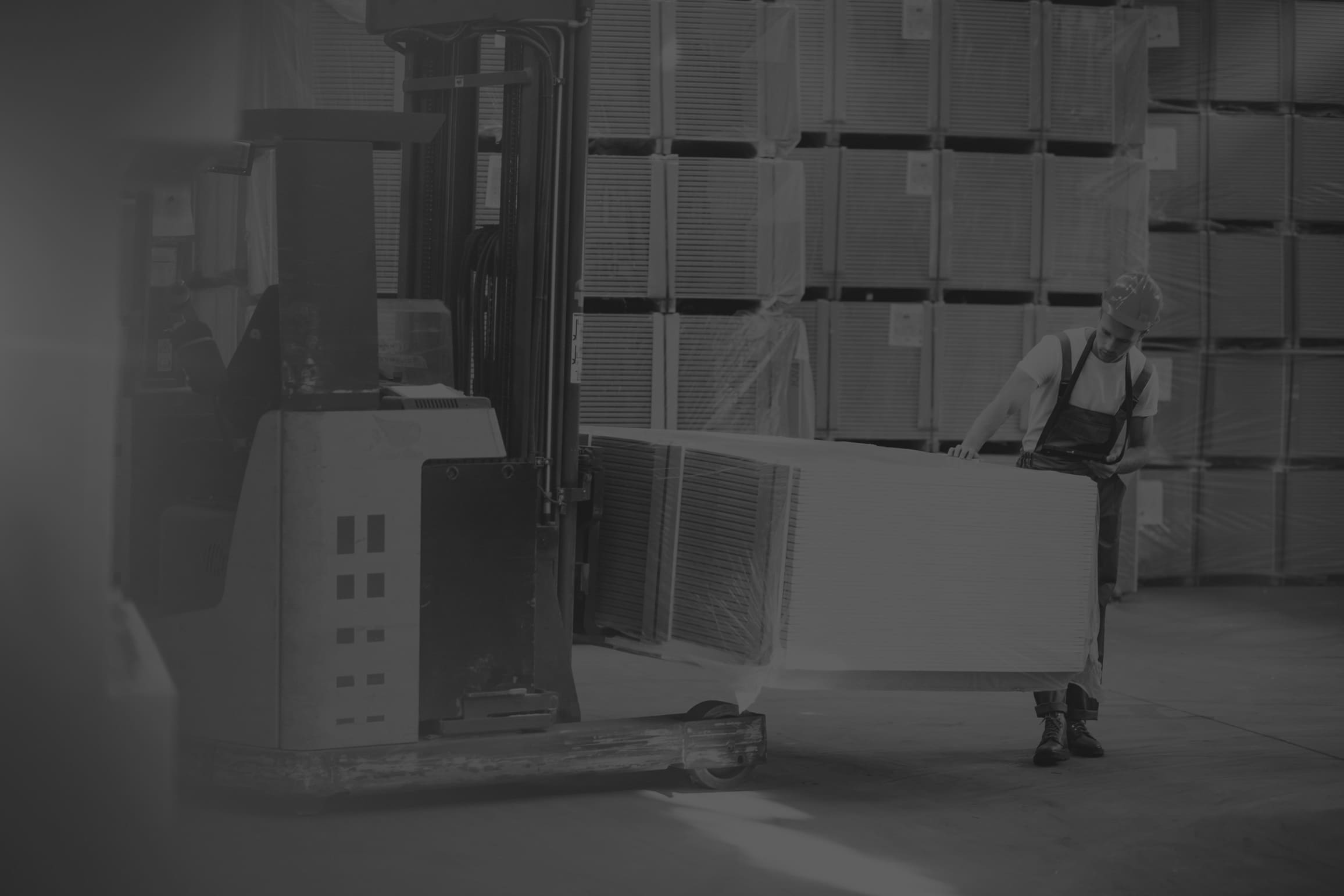 Black and White image of male warehouse worker lifting freezer on forklift.