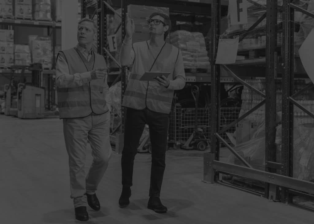 men with tablet in warehouse working in black and white