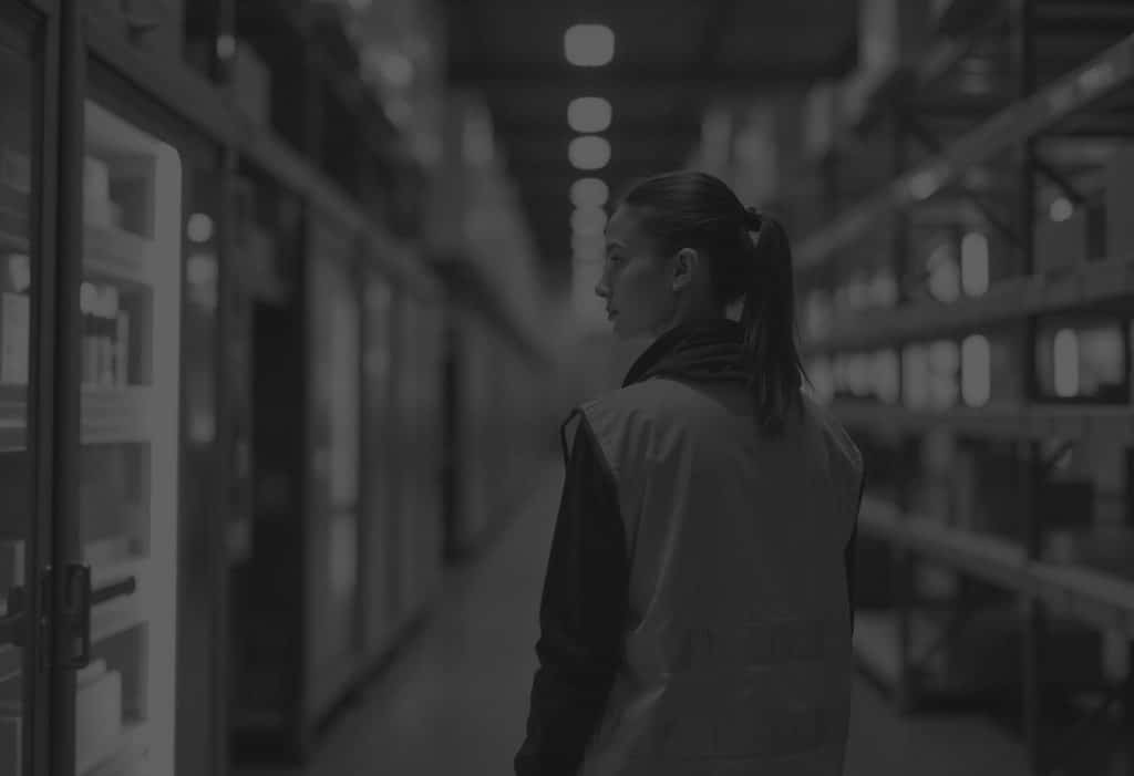 woman inside a warehouse wearing a hi vis inspecting refrigerator