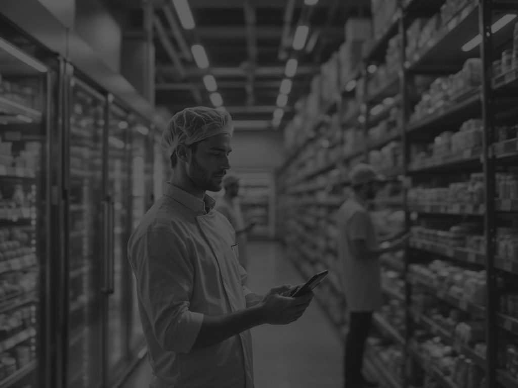 worker looking at his device while in the refrigerator aisle