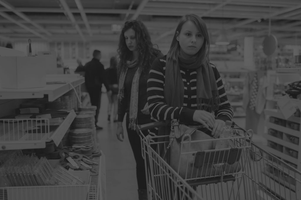women in shop looking concerned pushing shopping trolley black and white