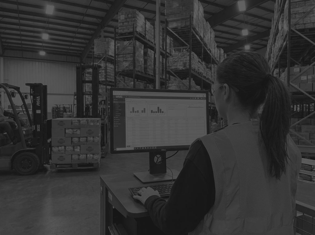 woman in hi-vis in warehouse looking at wms