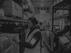 black and white photo of warehouse workers in warehouse using wms